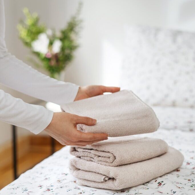 Vertical,Shot,Of,Woman,Put,Clean,And,White,Towels,On