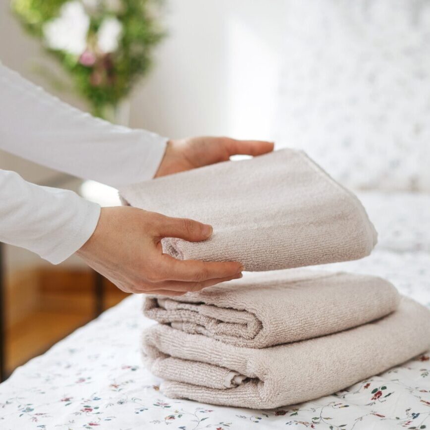 Vertical,Shot,Of,Woman,Put,Clean,And,White,Towels,On