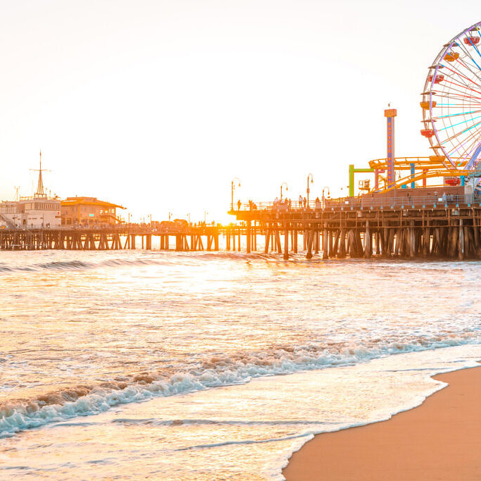 Santa Monica Pier on the background of an orange sunset, calm ocean waves, Los Angeles, California