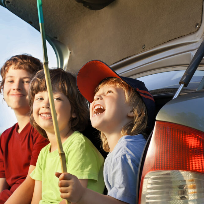 Three,Cheerful,Child,Sitting,In,The,Trunk,Of,A,Car