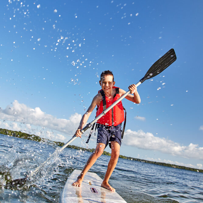 Happy,Boy,Paddling,On,Stand,Up,Paddleboard.,Cheerful,Child,Having