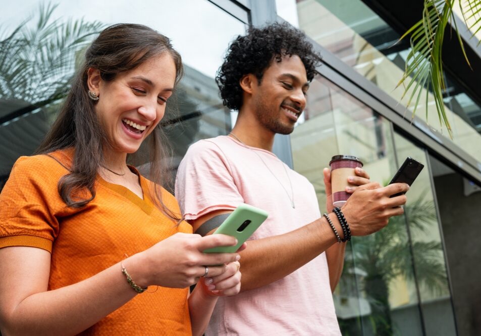 Happy,Friends,Using,Mobile,Phone,For,Fun,In,Coffee,Shop